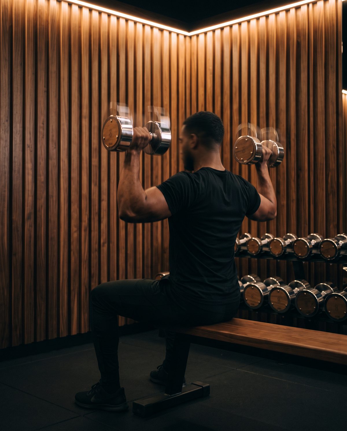 Athlete pressing chrome and walnut dumbbells