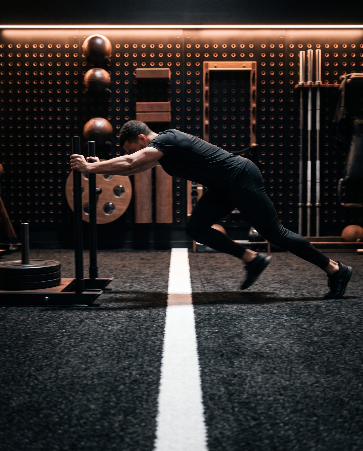 Athlete driving a sled on the black turf